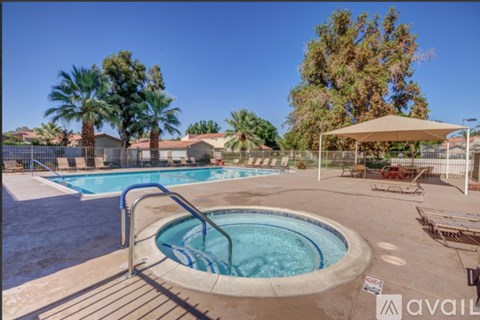 A pool with a hot tub and a fence surrounding it.