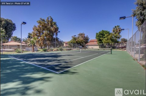 Tennis court with trees and a clear sky in the background.