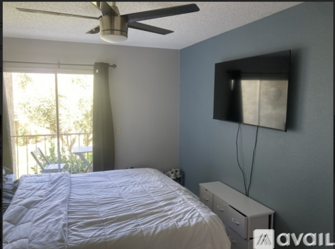 A bedroom with a bed, a ceiling fan, and a window with curtains.
