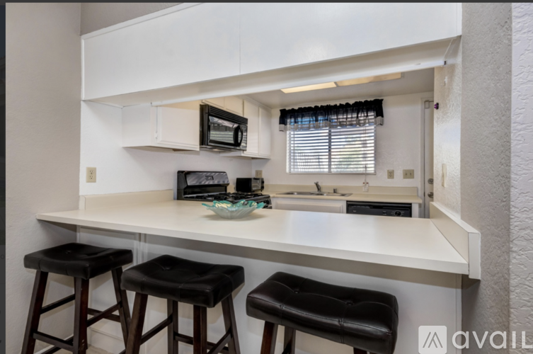 A kitchen with white countertops and black bar stools.