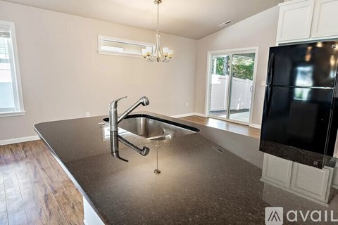 A kitchen with a granite countertop and a black refrigerator.