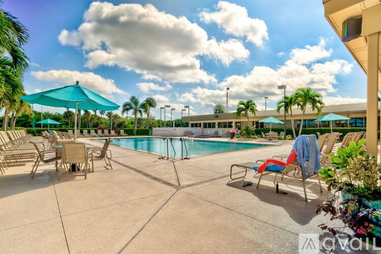 A pool area with sun loungers and a blue umbrella.