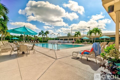 A pool area with sun loungers and a blue umbrella.