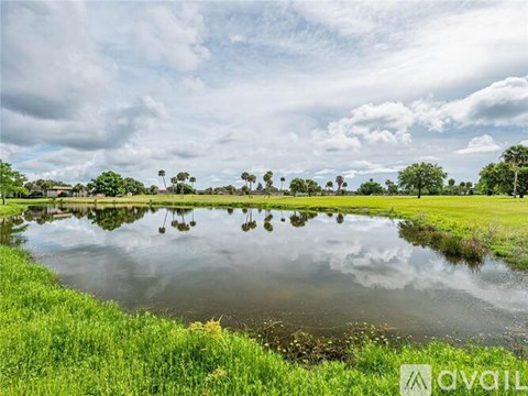 A calm lake reflects the sky and trees in the distance.