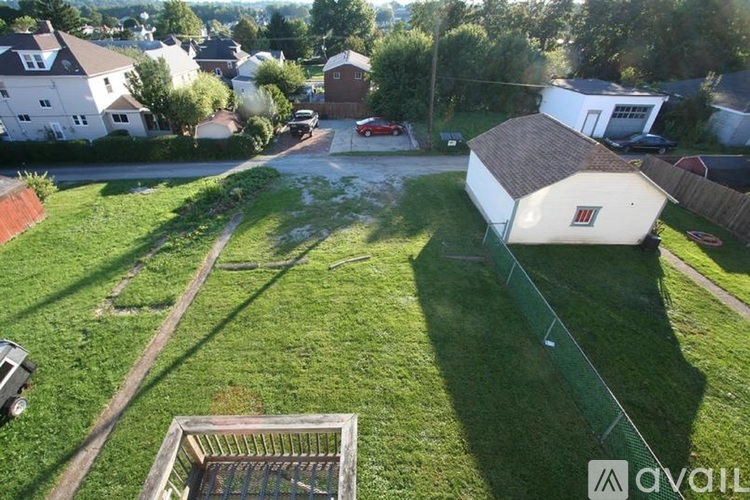 A grassy area with a shed and a car in the background.