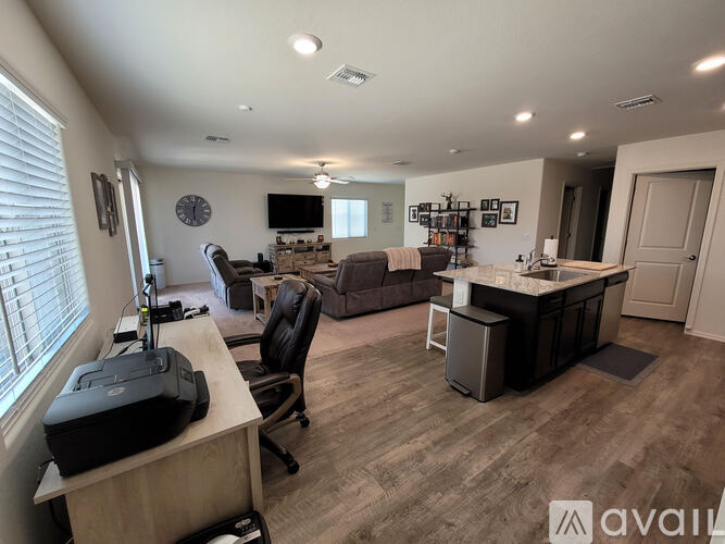 A spacious home office with a desk, chair, and a large window.