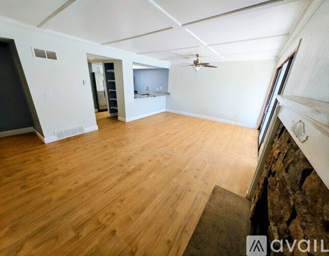 A spacious room with wooden flooring and a ceiling fan.