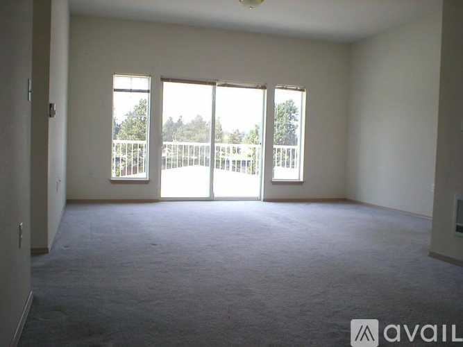 A room with carpeted floor and a balcony with a railing.