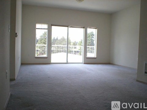 A room with carpeted floor and a balcony with a railing.