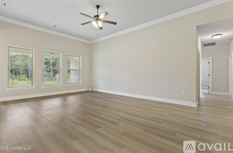 A spacious room with a ceiling fan and hardwood flooring.
