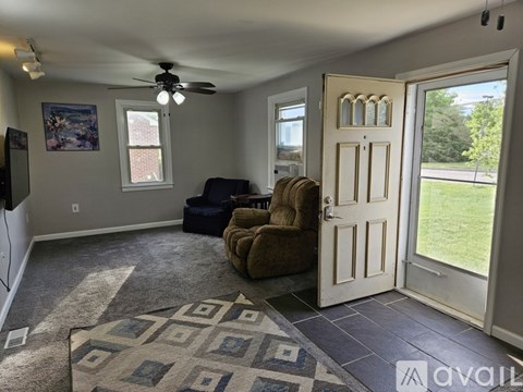 A living room with a ceiling fan and a rug on the floor.