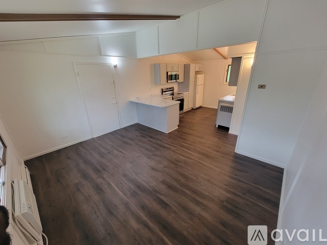 A spacious room with wooden flooring and white walls.