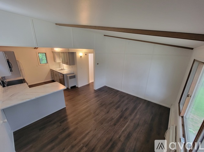 A room with wooden floors and white walls, with a window on the right side.