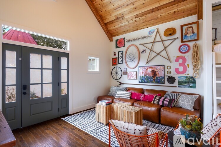 A living room with a couch, a chair, and a wall with many pictures and decorations.