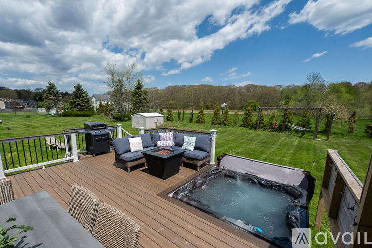 A hot tub on a deck with a couch and chairs.