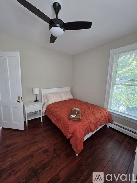 A bedroom with a bed, nightstand, and window.