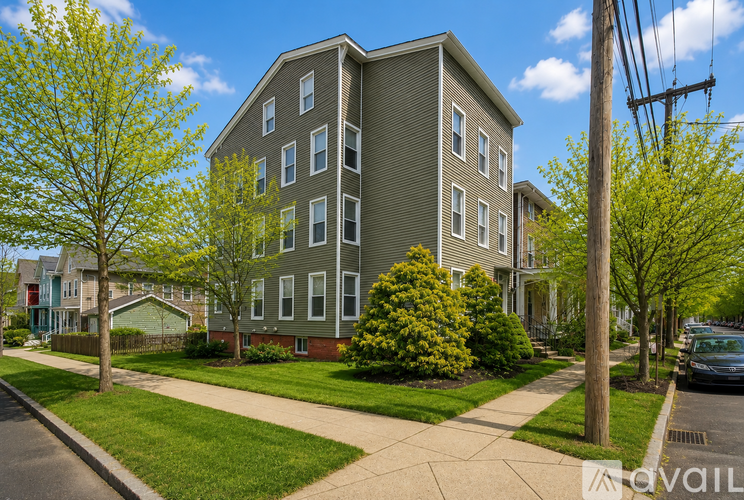 A grey apartment building with a tree in front of it.