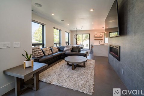 A modern living room with a black leather sofa and a wooden coffee table.