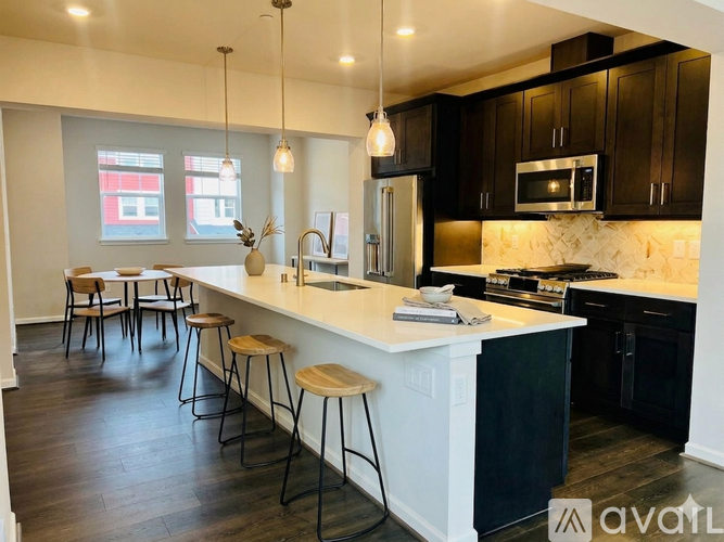 A kitchen with black cabinets and a white island.
