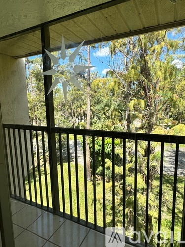 A balcony with a metal railing and a view of a green lawn and trees.