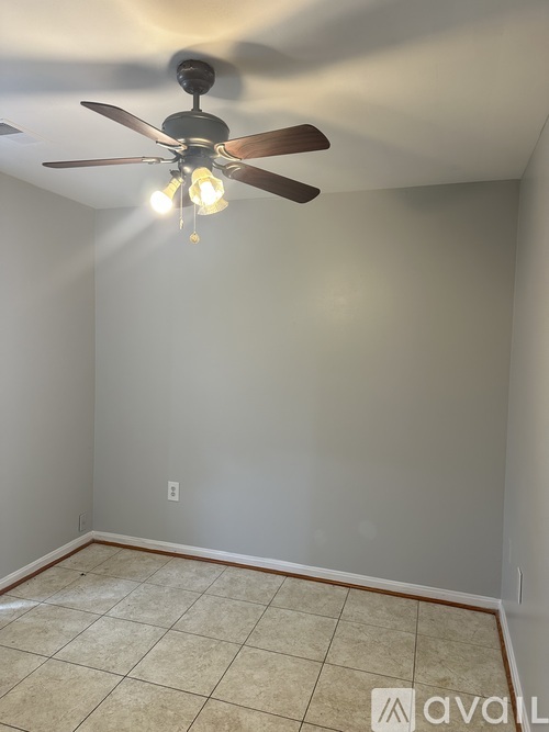 A room with a ceiling fan and tiled floor.