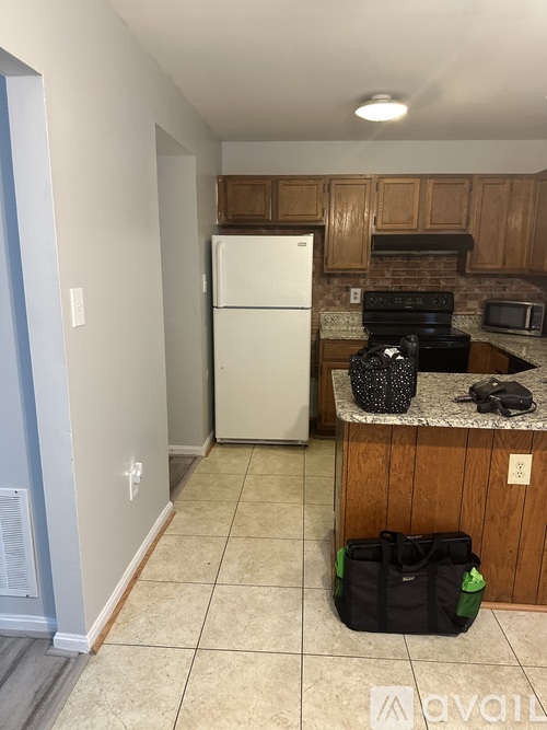 A kitchen with a white fridge and a black bag on the floor.