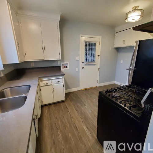 A kitchen with white cabinets and a black stove top oven.