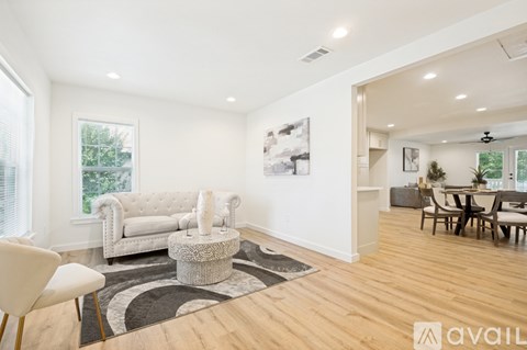 A living room with a white couch and a black and white rug.
