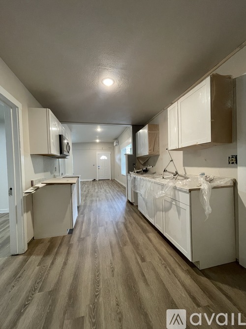A kitchen with white cabinets and wooden flooring.