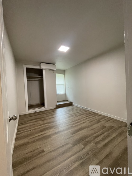A room with a white door and a wooden floor.