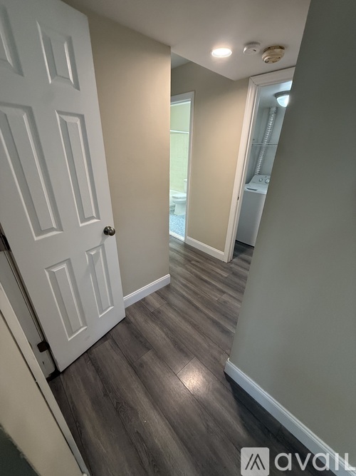 A hallway with a white door and grey flooring.