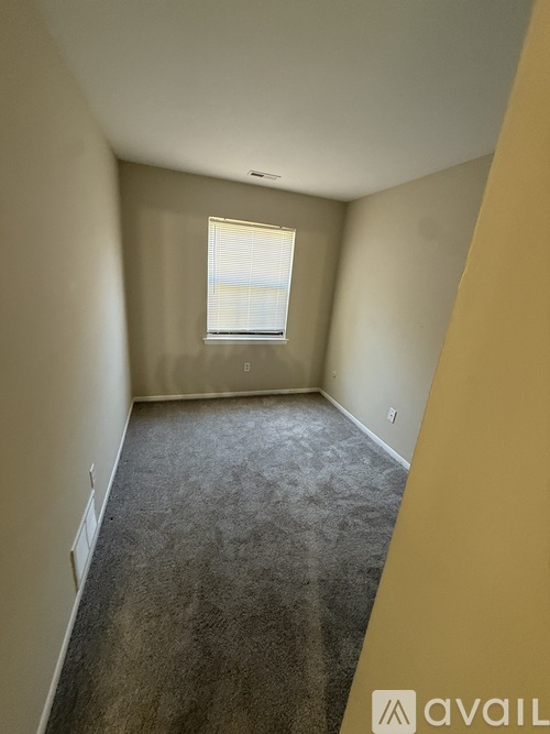 A room with a carpeted floor and a window with blinds.