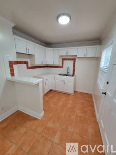 A kitchen with white cabinets and a tiled floor.