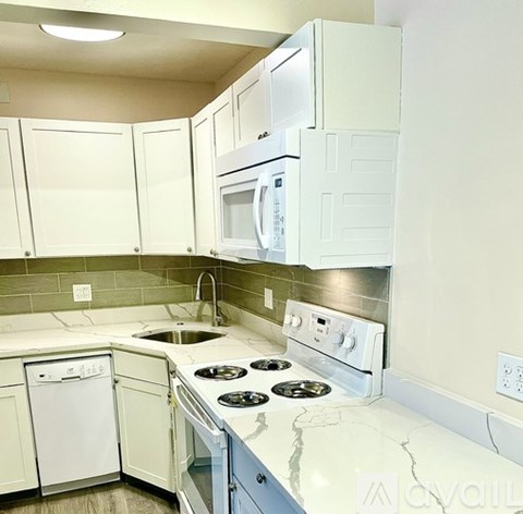 A kitchen with white appliances and cabinets.