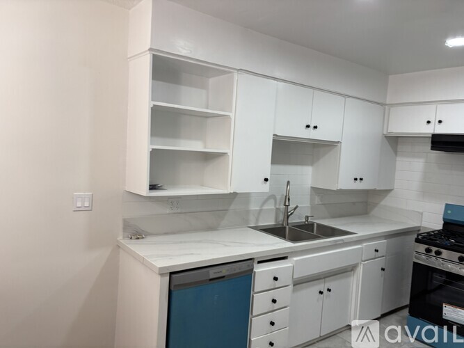 A kitchen with white cabinets and a blue dishwasher.