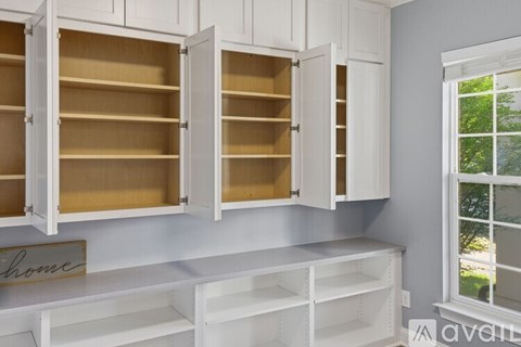 A kitchen with white cabinets and a window.