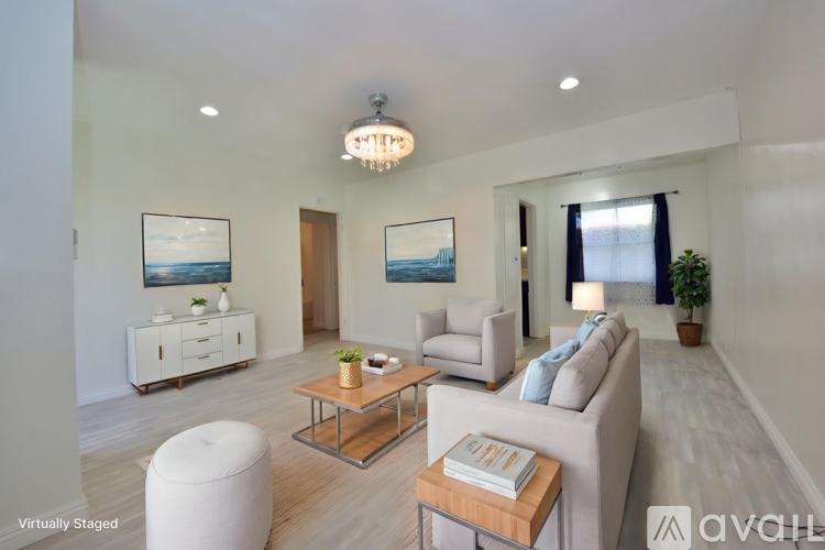 A living room with a white couch, a coffee table, and a painting on the wall.
