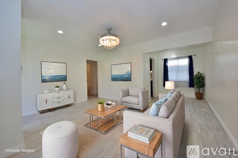 A living room with a white couch, a coffee table, and a painting on the wall.
