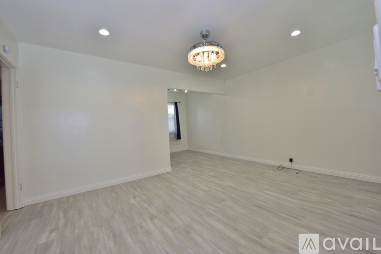 A spacious room with a chandelier and wooden flooring.