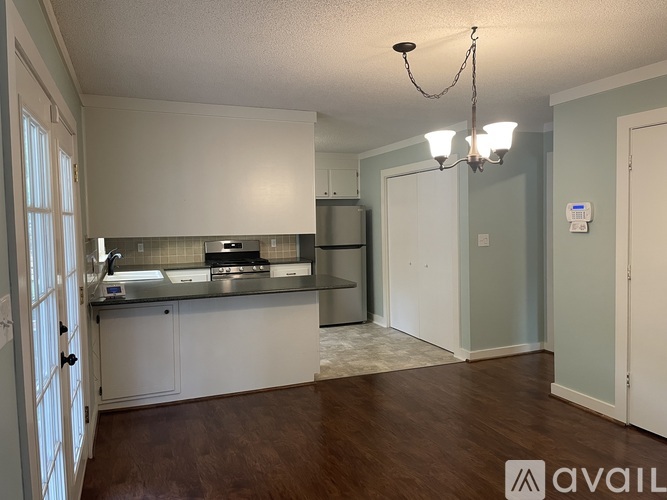A kitchen with white cabinets and a wooden floor.