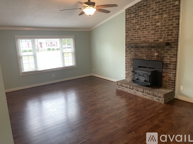 A living room with a fireplace and a ceiling fan.