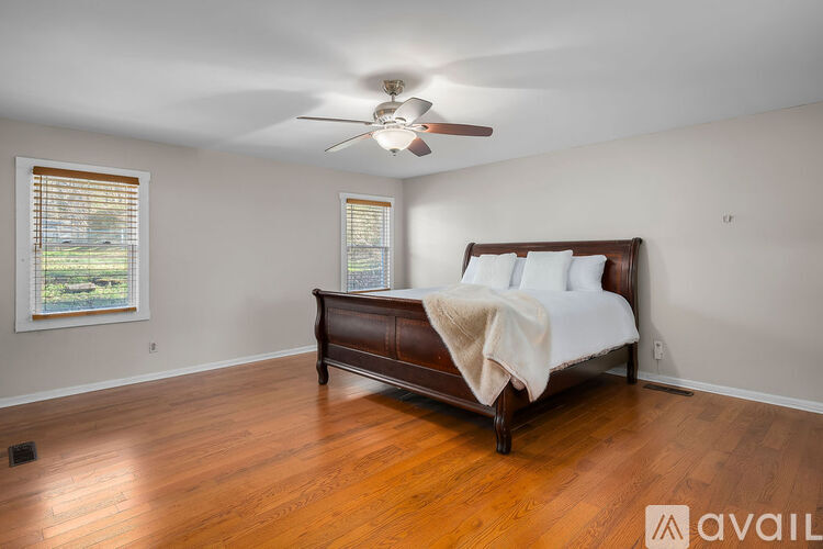 A bedroom with a bed, a ceiling fan, and a window with blinds.