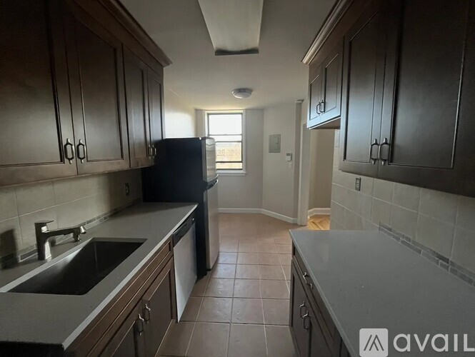 A kitchen with dark wood cabinets and a black refrigerator.