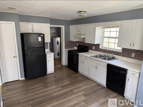 A kitchen with black appliances and white cabinets.