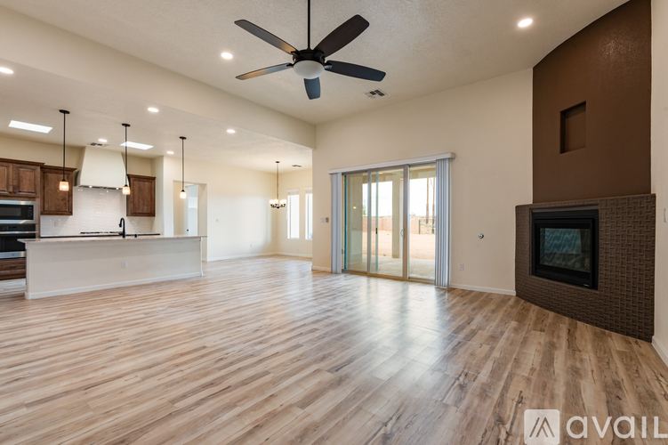 A spacious living room with wooden flooring and a ceiling fan.