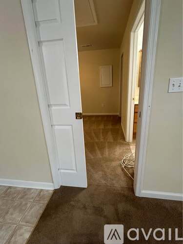 A hallway with a white door and a brown carpet.
