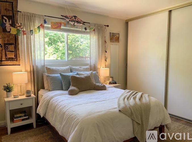 A bedroom with a large bed and a window with curtains.