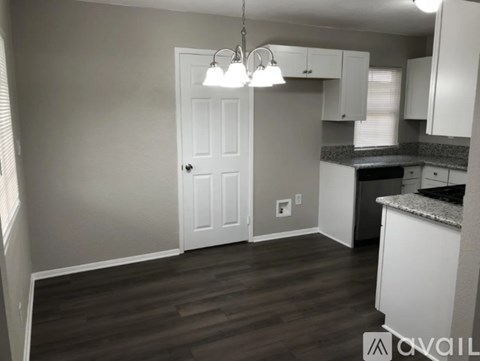 A kitchen with a white door and cabinets.