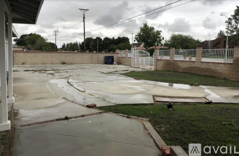 A view of a backyard with a pool table and a fence.