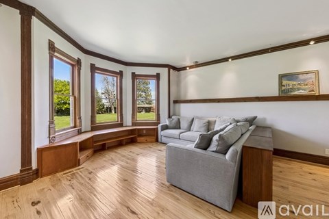 A living room with a grey couch and wooden floors.
